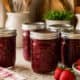 Assorted homemade berry jams in glass mason jars on kitchen countertop.