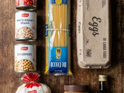 Basic grocery essentials including canned tomatoes, beans, pasta, rice, peanut butter, eggs, and oli.