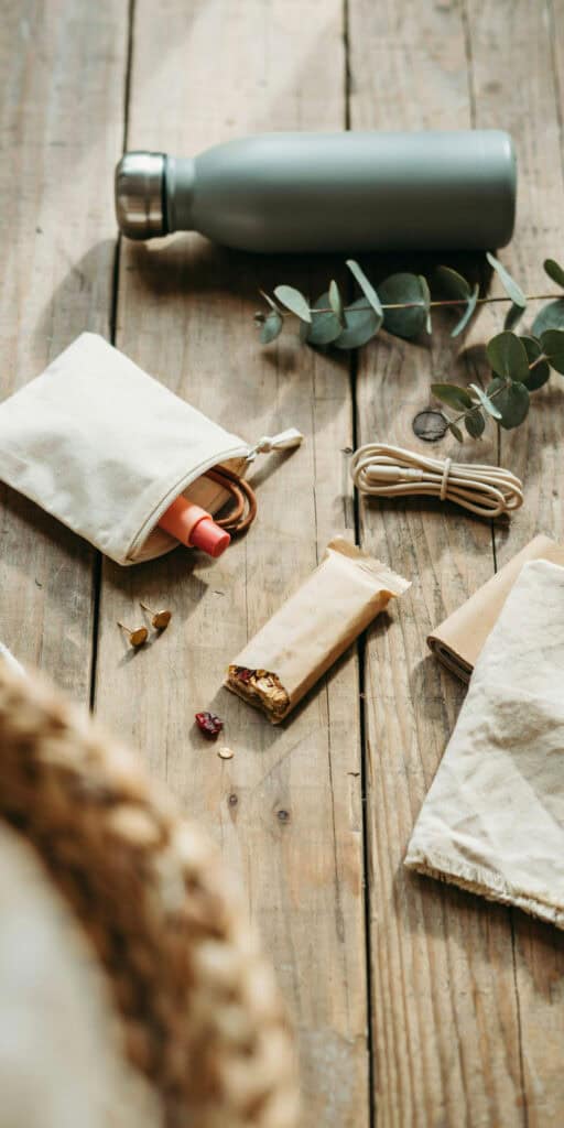 The Ultimate Back to School Survival Kit for Teens (A Complete School Bag Checklist) 3 Reusable water bottle, snacks, and eco-friendly items on wooden table.