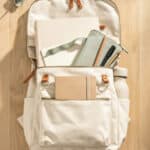 7 School backpack with notebooks, water bottle, and accessories on wooden desk.
