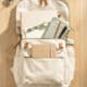 School backpack with notebooks, water bottle, and accessories on wooden desk.