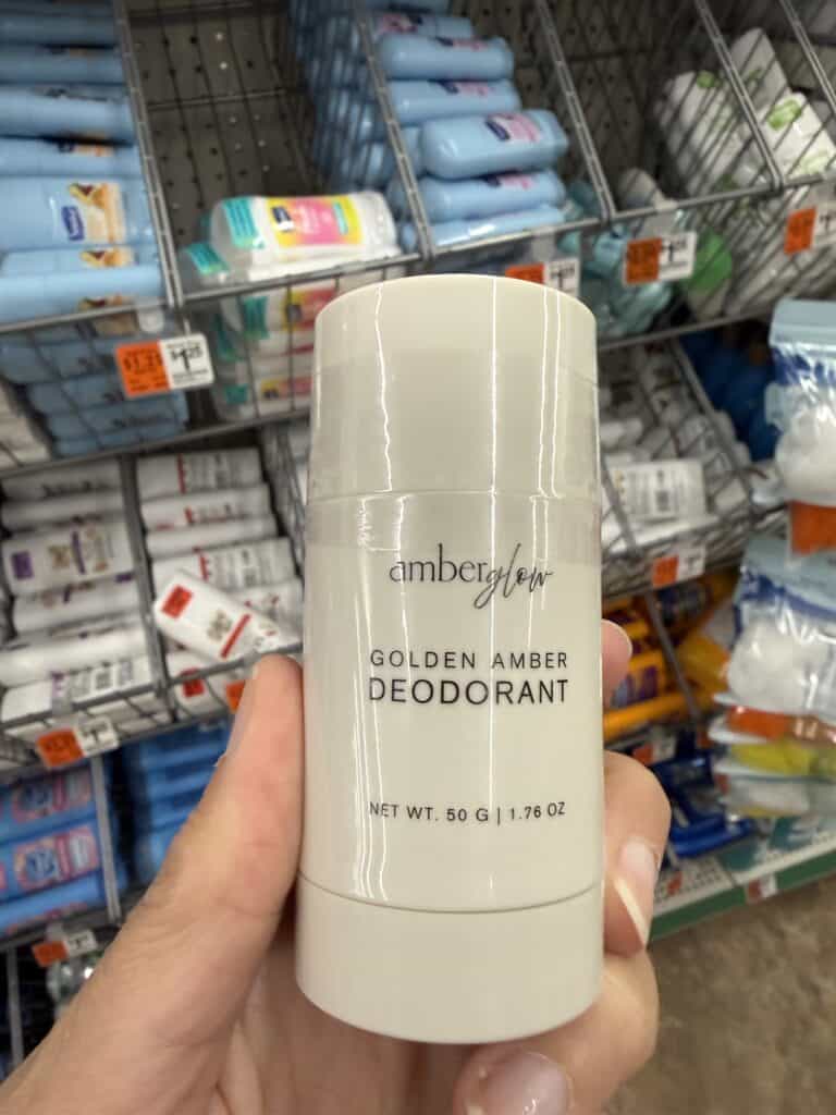 15 Dollar Tree Personal Care Finds I Actually Keep Buying (All Just $1.25!) 14 Amber Flower Golden Amber Deodorant stick in hand at store.