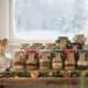 Assorted layered soup mix jars on a windowsill with snow outside.