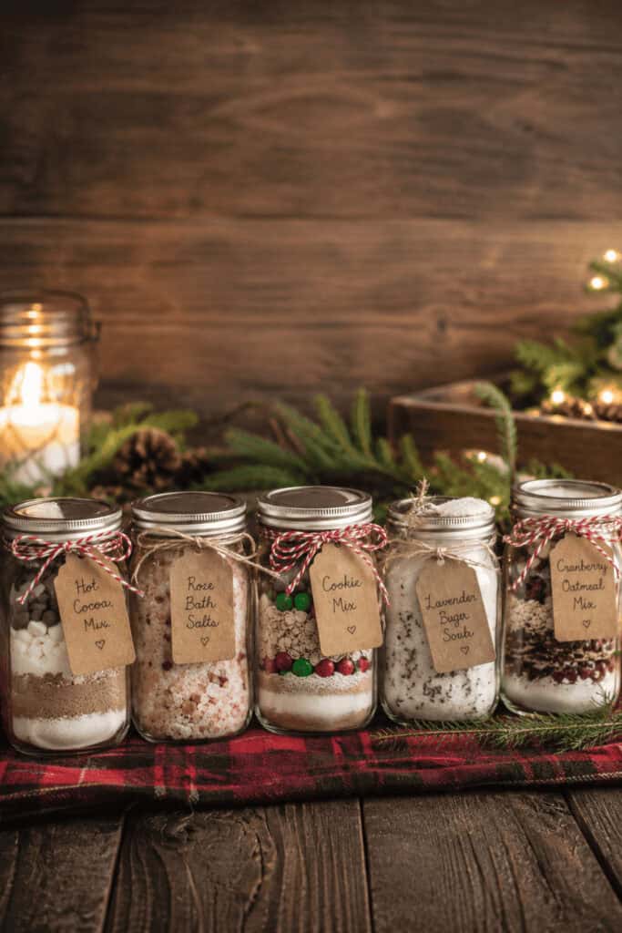 25 Mason Jar Christmas Gifts That Look Expensive (But Aren't) 6 Set of five mason jars with holiday-scented bath salts and labels on a rustic wooden table.