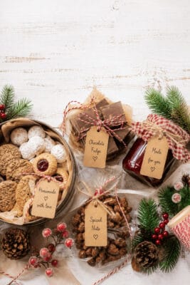 Assorted homemade Christmas food gifts with cookies, fudge, and nuts on a holiday table.