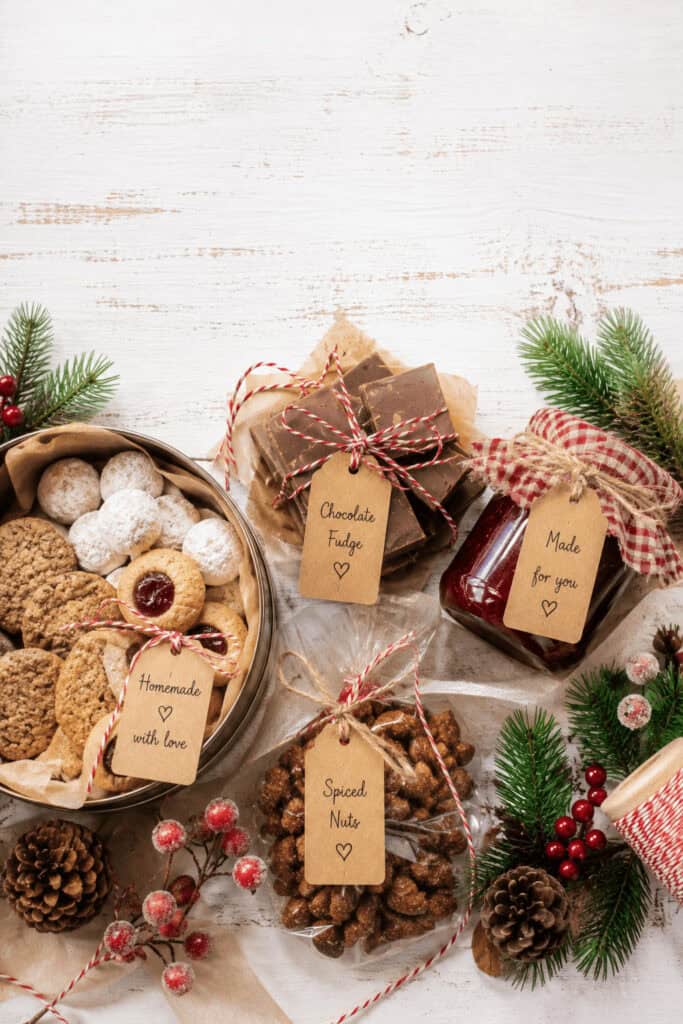 25 Homemade Food Gifts for Christmas That Everyone Loves 1 Assorted homemade Christmas food gifts with cookies, fudge, and nuts on a holiday table.