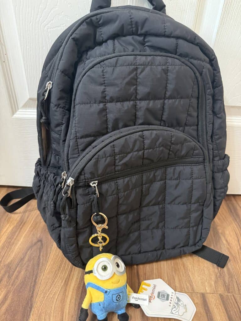 15 Backpack Charm Ideas: Easy DIY + Where to Find the Cutest Ones 8 Black quilted backpack with multiple compartments and a Minion keychain.