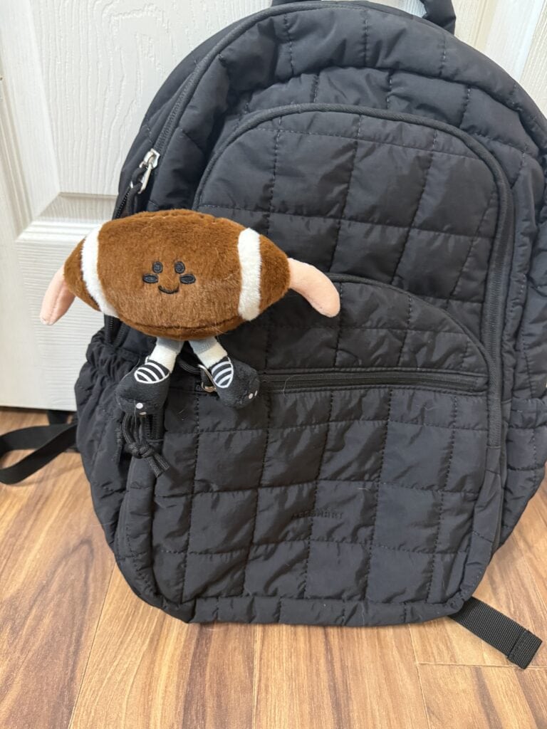 15 Backpack Charm Ideas: Easy DIY + Where to Find the Cutest Ones 9 Black quilted backpack with a cute plush toy attached.