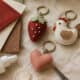 Felt strawberry, heart, and bird backpack charms on craft table.