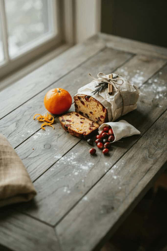 Homemade Food Gifts: 6 Easy Edible Christmas Gifts (With Recipes!) 6 Homemade fruit cake with orange and cranberries on rustic wooden table.