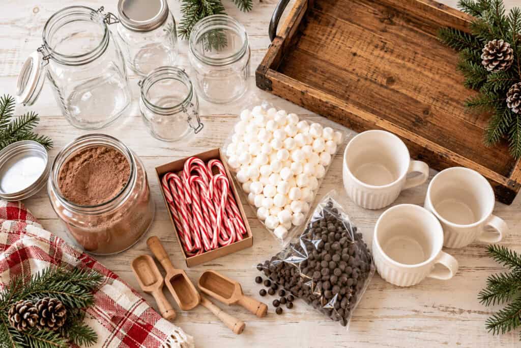 Hot Cocoa Bar Ideas: How to Set Up a Cozy Christmas Cocoa Station on a Budget. 2 Christmas hot cocoa bar with jars, mugs, candy canes, and toppings.